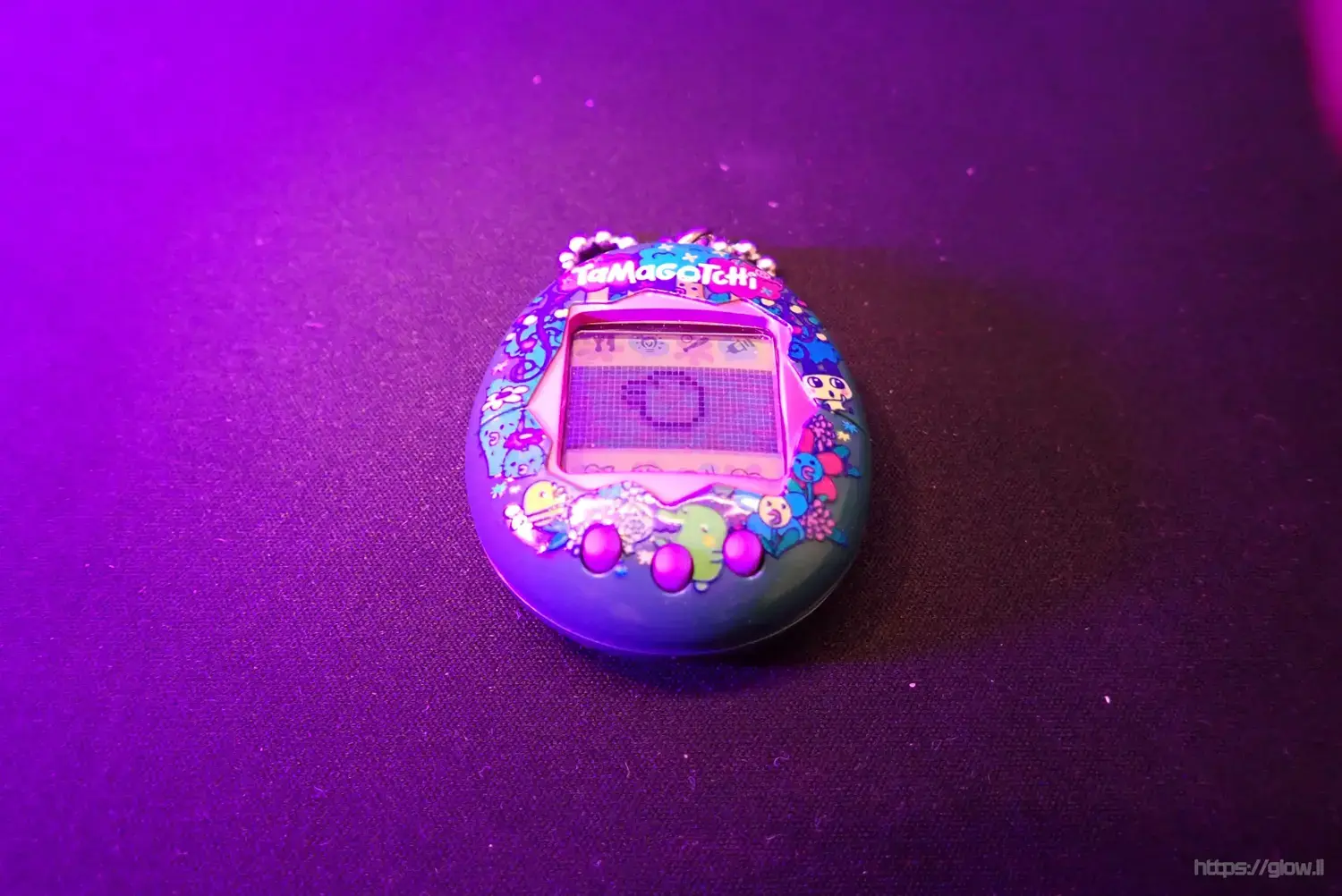 A Tamagotchi device bathed in pink light
